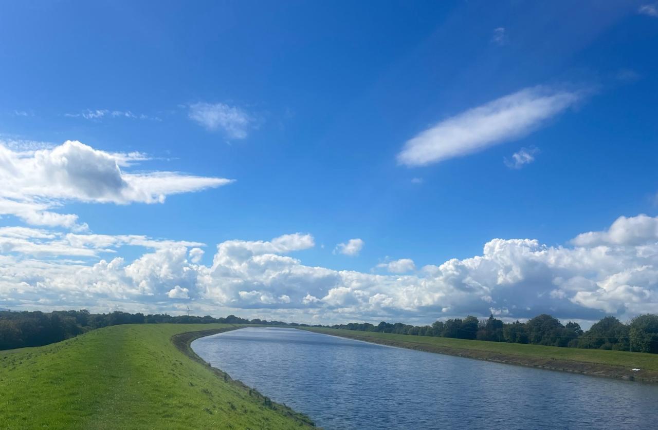 A long straight canal towpath under a blue sky — the hero image